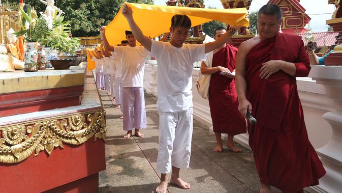 11 anak laki-laki bersama pelatih mereka, yang diselamatkan dari gua di Thailand, menjalani upacara pentahbisan di Kuil Wat Phra That Doi Wao, Selasa (24/7). Sebanyak 11 dari 12 remaja itu menjalani ritual menjadi biksu selama 9 hari. (AP /Sakchai Lalit)