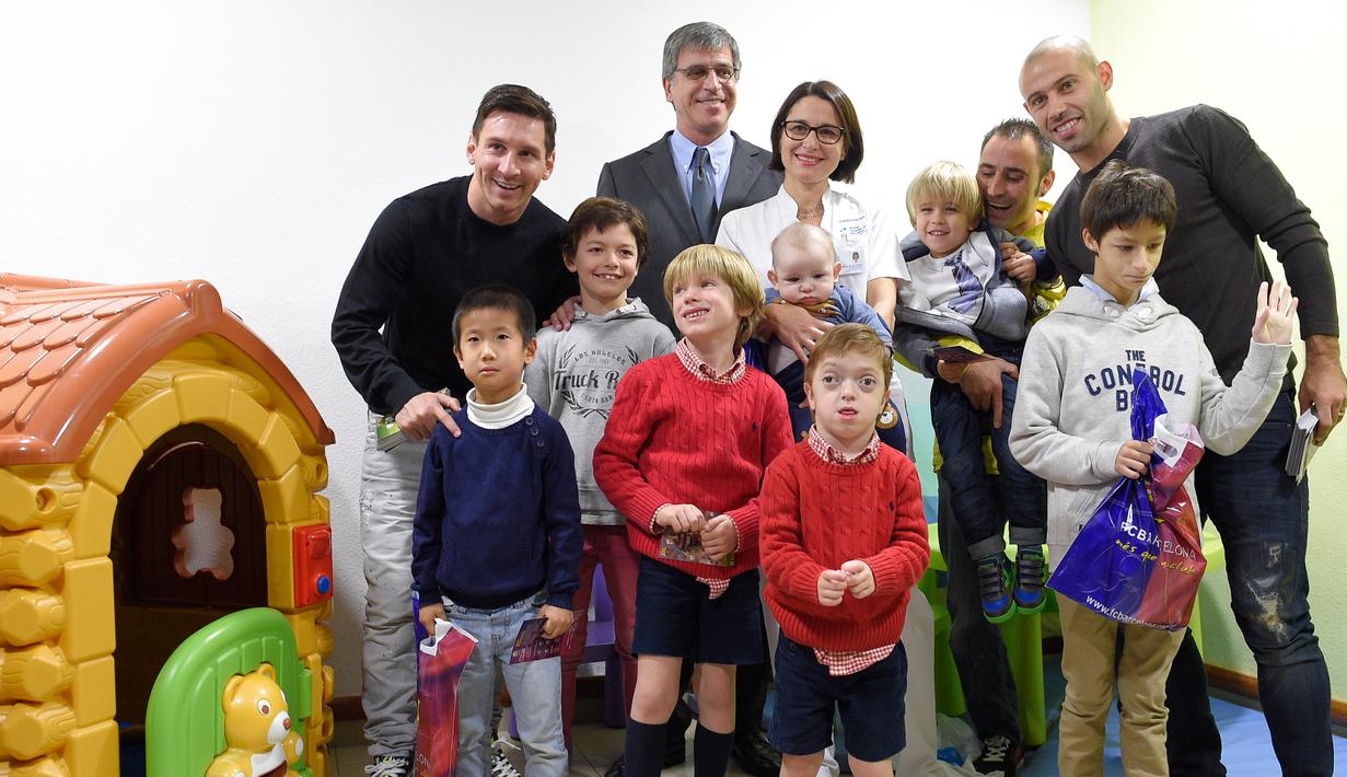 Pemain Barcelona, Lionel Messi (kiri) dan Javier Mascherano (kanan) berpose dengan sejumlah anak saat melakukan kunjungan amal di Rumah Sakit Barcelona, Senin (4/1/2016). (AFP PHOTO / Lluis GENE)