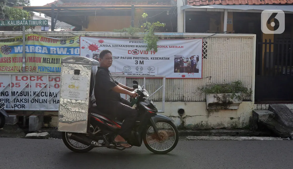 Pengendara motor melintasi spanduk zona merah kawasan RW 10 Kelurahan kalibata, Jakarta, Selasa (9/2/2021). Pemerintah mulai menerapkan PPKM skala mikro mulai 9-22 Februari 2021 untuk DKI Jakarta, Jawa Barat, Banten, Jawa Tengah, Yogyakarta, Jawa Timur, dan Bali. (Liputan6.com/Herman Zakharia)