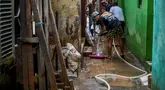 Warga membersihkan jalan di depan rumah mereka yang dipenuhi lumpur setelah banjir melanda lingkungan mereka setelah hujan deras di Jakarta pada Senin 7 Juli 2025. (BAY ISMOYO/AFP)