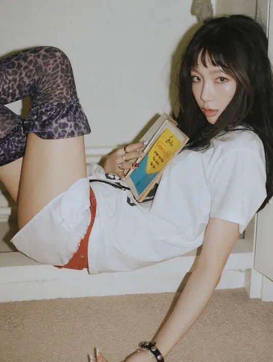 Wajahnya tetap dipoles makeup flawless ciri khas perempuan Korea dengan lipstik nude. Rambutnya panjang dibiarkan terurai bergaya messy dengan poni depan berjarak. [@taeyeon_ss]