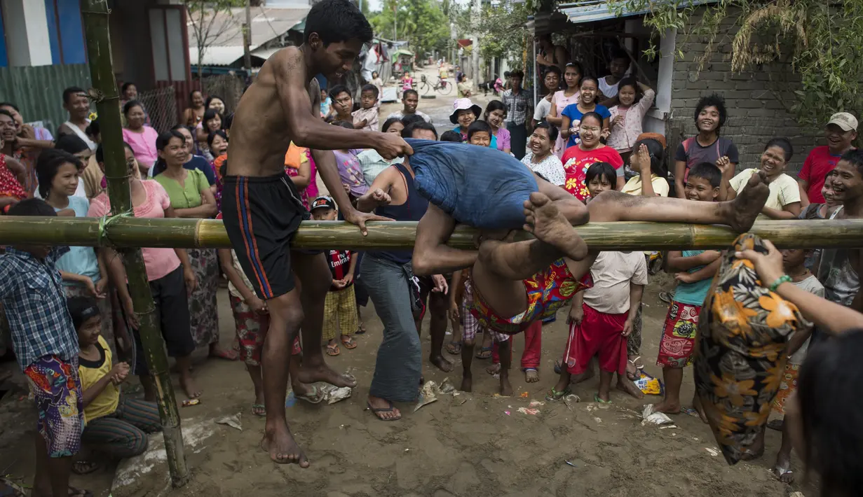 Seorang peserta coba bertahan dari serangan lawannya saat mengikuti Perang Bantal di Yangon, Rabu (4/1). Acara tersebut digelar dalam rangka HUT Kemerdekaan Myanmar ke-69. (AFP PHOTO / YE AUNG THU)