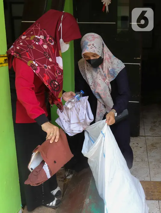 Petugas mengumpulkan barang-barang saat membersihkan ruangan di MTsN 19 Pondok Labu, Jakarta, Jumat (7/10/2022). Petugas PPSU, Satpol PP, dan Dinas Pemadam Kebakaran membersihkan ruang kelas, kantin, dan fasilitas lainnya usai terendam banjir pada Kamis sore kemarin. (Liputan6.com/Herman Zakharia)