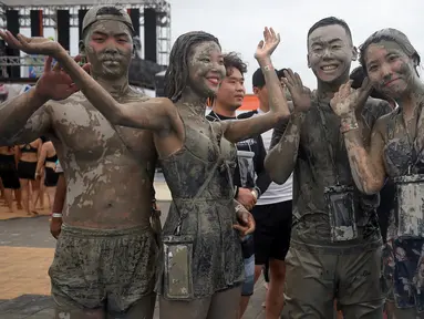 Wisatawan bermain di kolam lumpur selama Boryeong Mud Festival atau Festival Lumpur Boryeong di pantai Daecheon, Korea Selatan, Sabtu (20/7/2019).  Ajang mandi lumpur sepuasnya di Korea Selatan ini, merupakan festival khusus untuk memeriahkan musim panas di negeri ginseng. (Minji SUH/AFP)