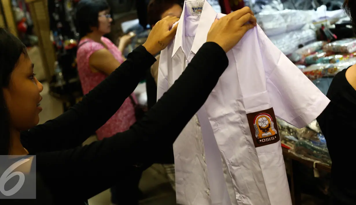 Seorang anak melihat seragam di kawasan Pasar Baru, Jakarta, Selasa (12/7). Menjelang tahun ajaran baru, sejumlah toko penjualan perlengkapan sekolah mulai didatangi warga. (Liputan6.com/Faizal Fanani)