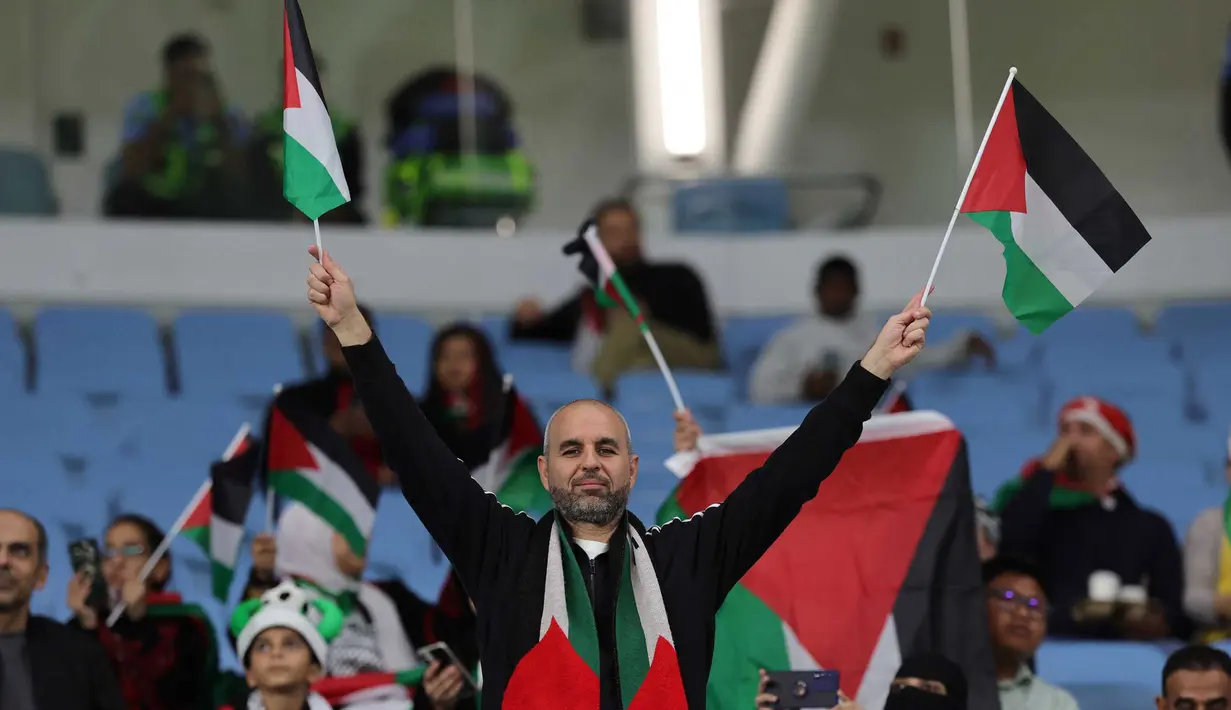 Seorang pendukung melambaikan bendera sebelum dimulainya pertandingan sepak bola Grup C Piala Asia AFC Qatar 2023 antara Palestina dan Uni Emirat Arab di Stadion Al-Janoub di Al-Wakrah, Doha pada 18 Januari 2024. (Giuseppe CACACE/AFP)
