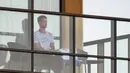 Petenis pria peringkat satu dunia, Novak Djokovic duduk di balkon salah satu hotel tempat karantina, Adelaide, Australia, Senin (18/1/2021). (Foto: AFP/Brenton Edwards)