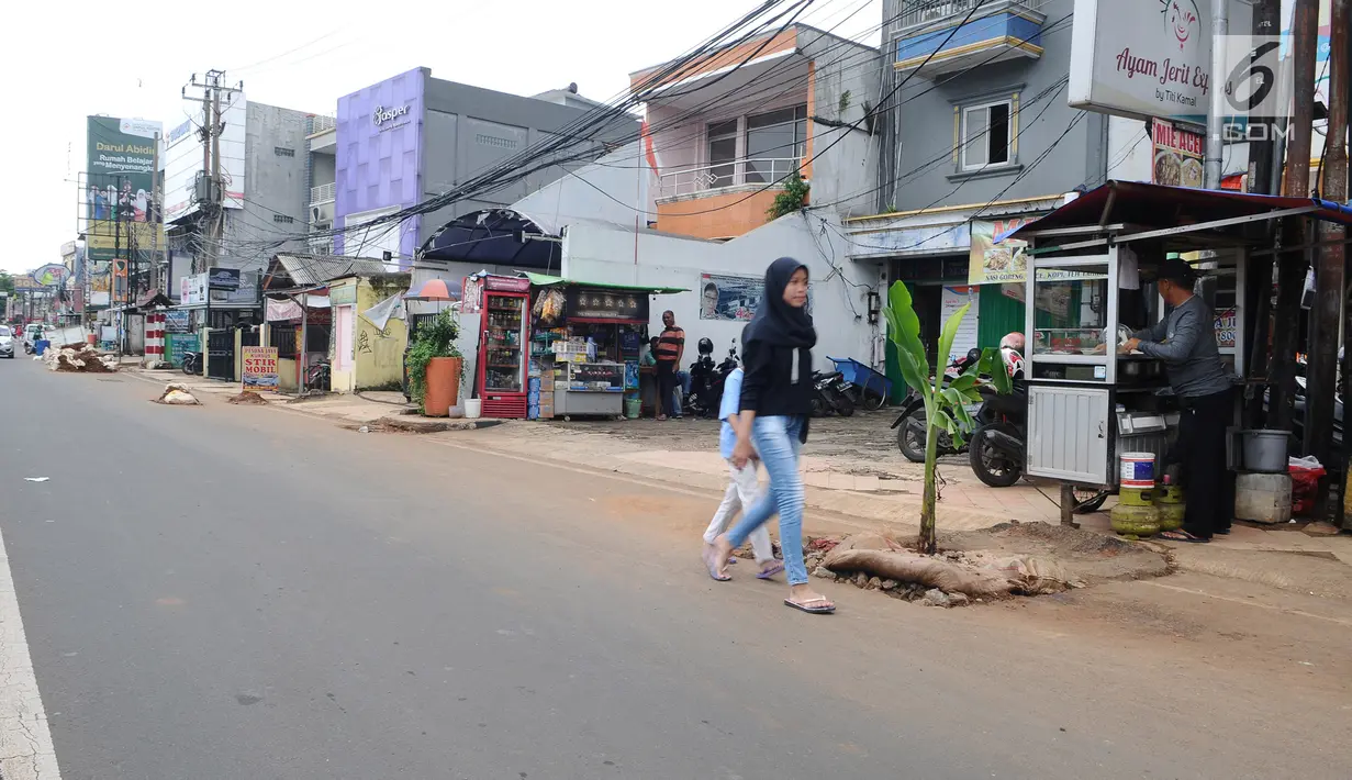 Pejalan kaki melintasi lubang bekas galian yang ditanami pohon pisang di pinggir Jalan Raya Margonda, Depok, Senin (4/3/2019). Aksi tanam pohon pisang itu sebagai protes warga akibat banyaknya lubang galian di Jalan Margonda (Liputan6.com/Herman Zakharia)