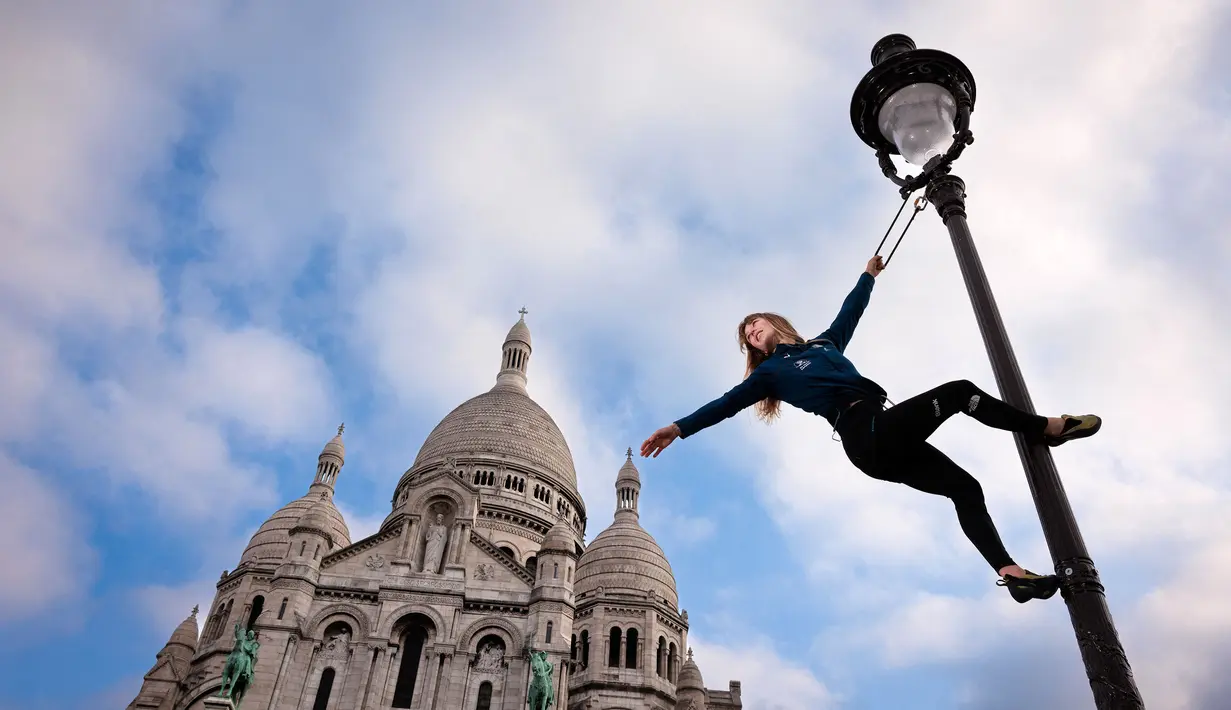 Atlet panjat tebing Prancis, Capucine Viglione berpose di lampu jalan di depan Basilika Sacre-Coeur (Hati Suci) di Paris pada 22 Mei 2024, menjelang Olimpiade dan Paralimpiade Paris 2024. Basilika Sacre-Coeur (Hati Suci) terletak di puncak bukit Montmartre di Paris. Paus Benediktus XV menaikkannya menjadi basilika kecil pada tahun 1919. (AFP/Franck Fife)