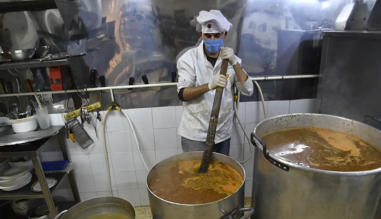 Relawan dari asosiasi Nass el-Khir memasak makanan untuk didistribusikan kepada mereka yang membutuhkan selama bulan suci Ramadan di Aljir, Aljazair, Senin (18/5/2020). (RYAD KRAMDI/AFP)