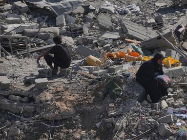 Seorang wanita Palestina yang terpaksa mengungsi duduk di atas puing-puing bangunan yang hancur di kawasan Sheikh Radwan yang parah kerusakannya di Kota Gaza, Sabtu 11 Oktober 2025. (AP Photo/Abdel Kareem Hana)