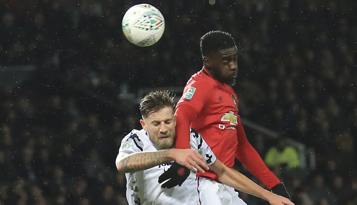 Bek Manchester United, Axel Tuanzebe berebut bola udara dengan gelandang Colchester United, Harry Pell pada pertandingan perempat final Piala Liga Inggris di Old Trafford (18/12/2019). Di semifinal, MU akan bertemu Manchester City. (AP Photo/Jon Super)