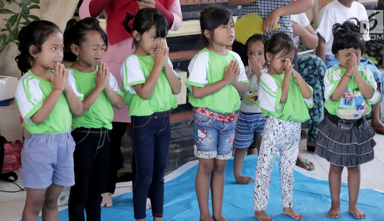 Anak-anak TK berdoa sebelum mengikuti sekolah di kamp pengungsian Gor Swace Pura, Klungkung, Bali, Kamis (28/09). Kegiatan tersebut bertujuan menghilangkan rasa trauma serta sebagai sarana bermain anak korban bencana alam. (Liputan6.com/Gempur M Surya)