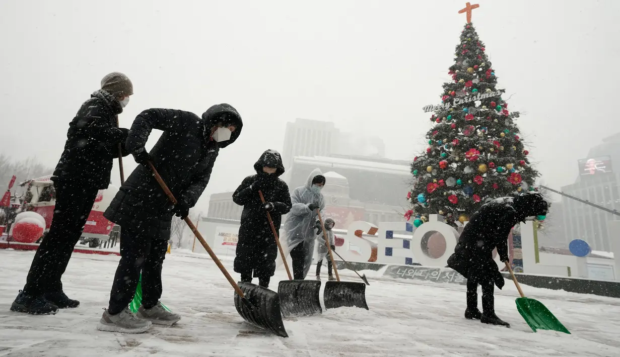 Pekerja membersihkan salju dari trotoar di sepanjang City Hall Plaza, Seoul, Korea Selatan, 15 Desember 2022. (AP Photo/Ahn Young-joon)