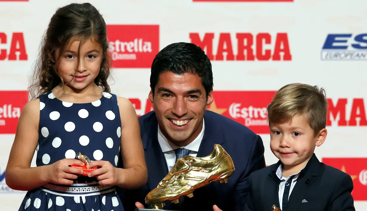 Penyerang Barcelona, Luis Suarez bersama kedua anaknya Delfina dan Benjamin, berpose dengan trofi Sepatu Emas Eropa 2016 selama penghargaan Golden Shoe atau sepatu emas untuk tahun 2016 di Barcelona, Spanyol (20/10). (REUTERS/Albert Gea)