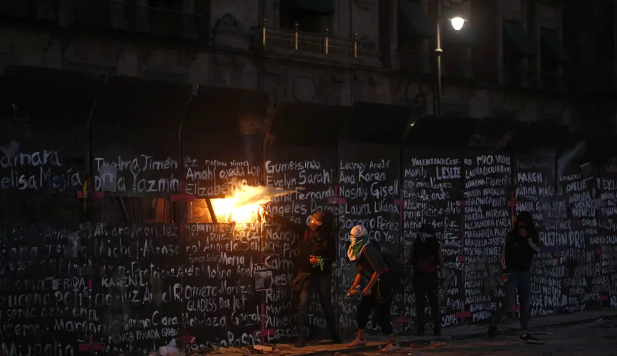 Demonstran menyerang barikade yang melindungi Istana Nasional selama pawai memperingati Hari Perempuan Internasional dan memprotes kekerasan gender di Mexico City, Meksiko, Senin (8/3/2021). Hari Perempuan Internasional diperingati setiap tanggal 8 Maret. (AP Photo/Rebecca Blackwell)