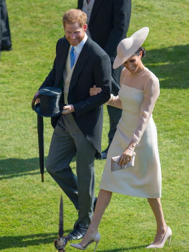 Duke dan Duchess of Sussex, Pangeran Harry dan Meghan Markle menghadiri pesta kebun Istana Buckingham di London, Selasa (22/5). Midi dress dari Goat dengan aksen lengan sheer itu tampak manis membalut tubuh Meghan Markle. (Ian Vogler/Pool Photo via AP)