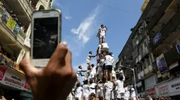 Warga mengambil gambar ribuan umat Hindu yang sedang membentuk piramida manusia untuk mencapai dan memecahkan dahi-handi (pot yang terbuat dari tanah liat) pada Festival Janmashtami di Mumbai, India, 6 September 2015. (REUTERS/Danish Siddiqui)