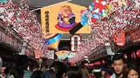 Pejalan kaki melintas di bawah dekorasi shio babi tanah yang mengarah ke kuil Buddha Asakusa Sensoji di Tokyo, Jepang, Kamis (27/12). Tahun babi tanah 2019 akan penuh sukacita cocok untuk persahabatan dan cinta semua shio. (AP Photo/Koji Sasahara)