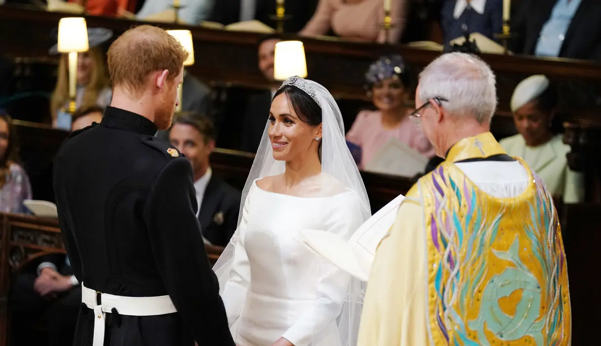 Pangeran Harry dan Meghan Markle saling berpandangan saat prosesi pernikahan mereka di Kapel St. George, Kastil Windsor, Inggris, Sabtu (19/5). Pangeran Harry dan Meghan Markle resmi menjadi suami istri. (Dominic Lipinski/POOL/AFP)