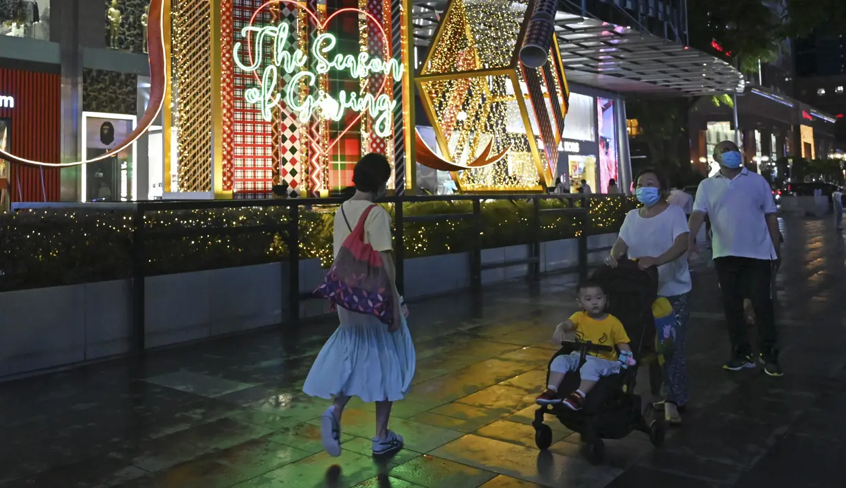 Orang-orang berjalan melewati dekorasi lampu Natal di luar pusat perbelanjaan di sepanjang kawasan Orchard road di Singapura, Selasa (8/12/2020). Mengusung tema Love This Christmas, acara tahun ini lebih sunyi karena aktivitas jalanan dibatasi di tengah pandemi Covid-19. (ROSLAN RAHMAN / AFP)