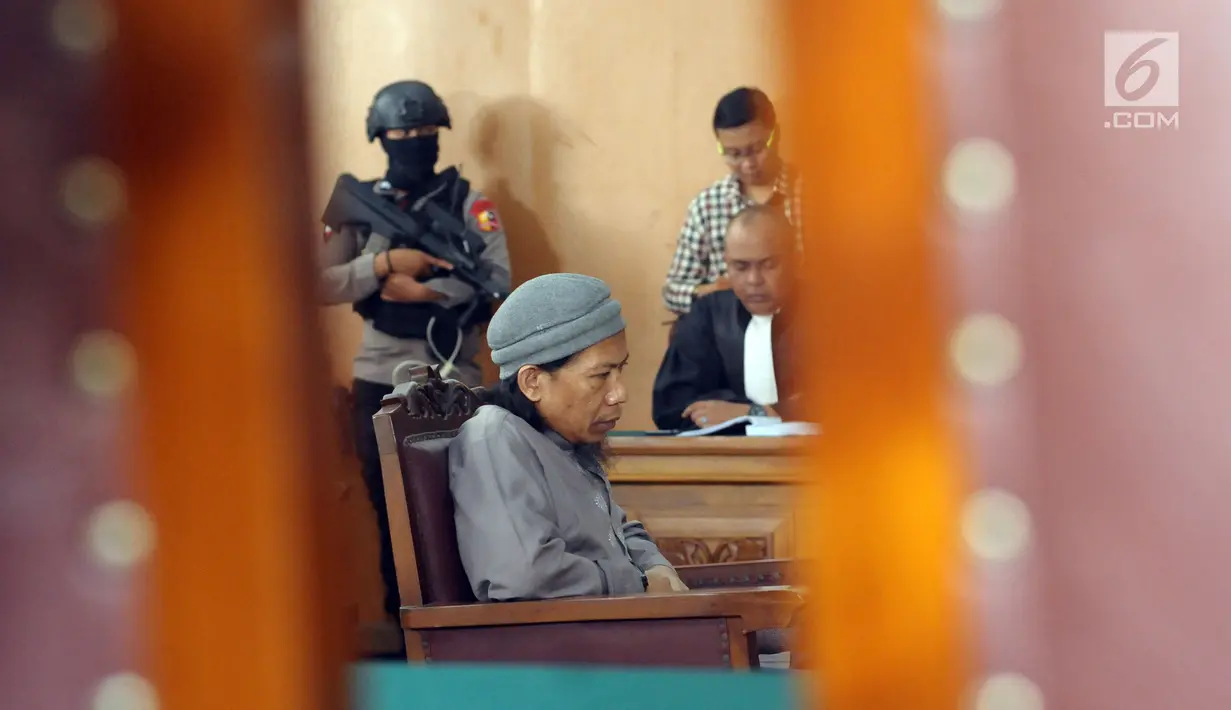 Terdakwa sejumlah kasus tindak pidana terorisme, Aman Abdurrahman saat mengikuti pembacaan tuntutan JPU di PN Jakarta Selatan, Jumat (18/5). Sidang dijaga ketat puluhan personel gabungan bersenjata lengkap. (Liputan6.com/Helmi Fithriansyah)