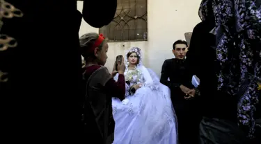 Pasangan pengantin Heba (kanan) dan Ahmed (kiri) saat melakukan prosesi pernikahan di Raqqa, Suriah (27/10). Usai Kota Raqqa diduduki ISIS, pasangan pengantin ini merupakan yang pertama menggelar pernikahan. (AFP Photo/Delil Souleiman)