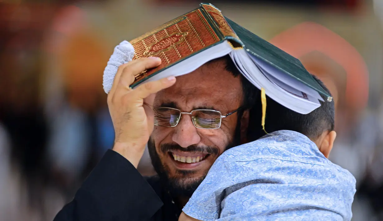 Jemaah syiah manaruh kitab suci Al-Quran di atas kepalanya saat menyambut malam lailatul qadar di Makam Suci Imam Ali, Najaf, Irak, Sabtu (16/5/2020). Ritual saat berdoa dan meminta hajat kepada Tuhan ini sudah berlangsung selama berabad-abad lamanya. (HAIDAR HAMDANI/AFP)