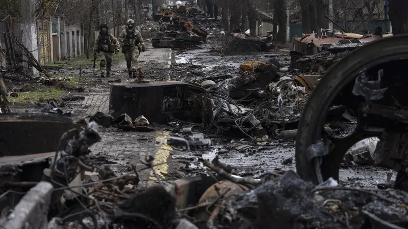 Prajurit Ukraina berjalan di antara tank-tank Rusia yang hancur di Bucha.