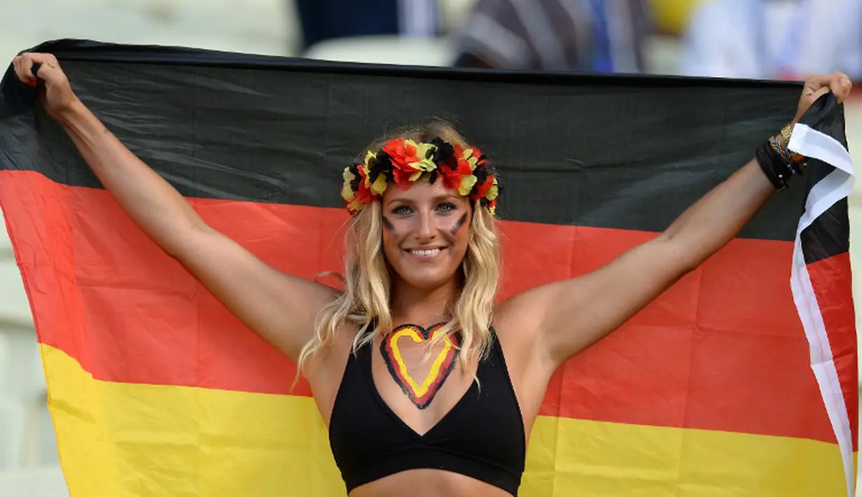 Sambil memegang bendera Jerman seorang suporter cantik ini memperlihatkan senyum indahnya sebelum Jerman berlaga melawan Ghana di The Castelao Stadium, Fortaleza (21/06/2014) (AFP PHOTO/CARL DE SOUZA)