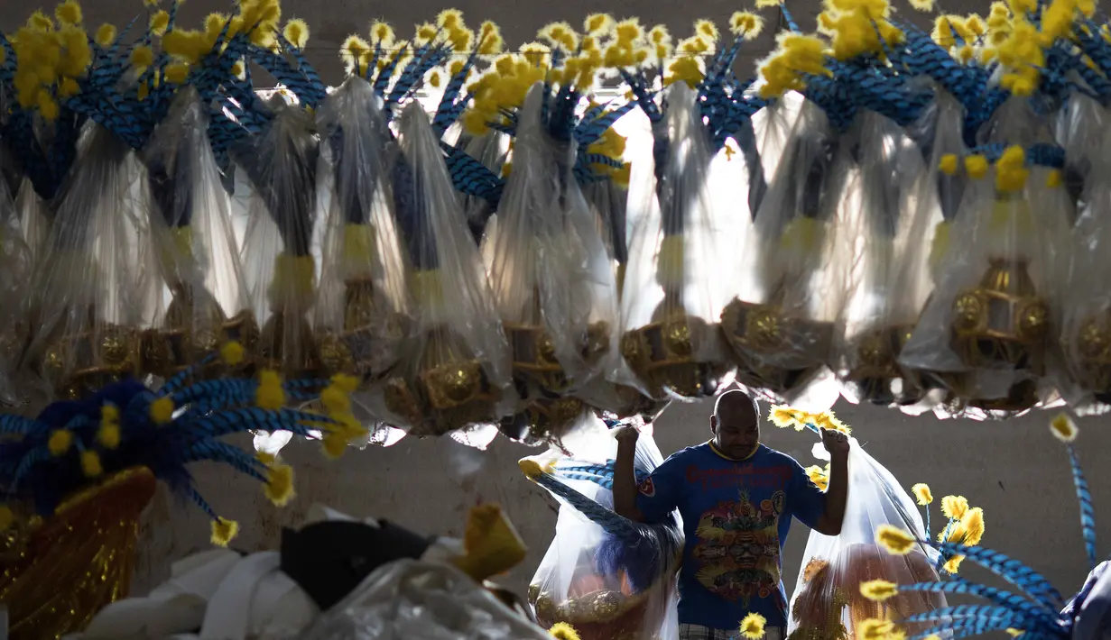 Pekerja membawa plastik yang berisi kostum untuk pertunjukan karnaval yang akan digunakan sekolah samba Paraiso do Tuiuti di Rio de Janeiro, Brasil (16/1). (AP Photo / Leo Correa)