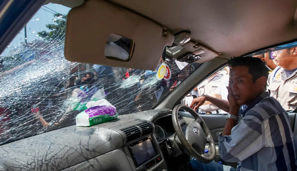 Seorang pengemudi menutupi wajahnya setelah dipukul massa demo transportasi online di JMakassar, Sulawesi Selatan, (1/11). Para sopir angkutan konvensional di Makassar melakukan aksi menuntut maraknya transportasi online. (AFP Photo/Yusuf Wahil)