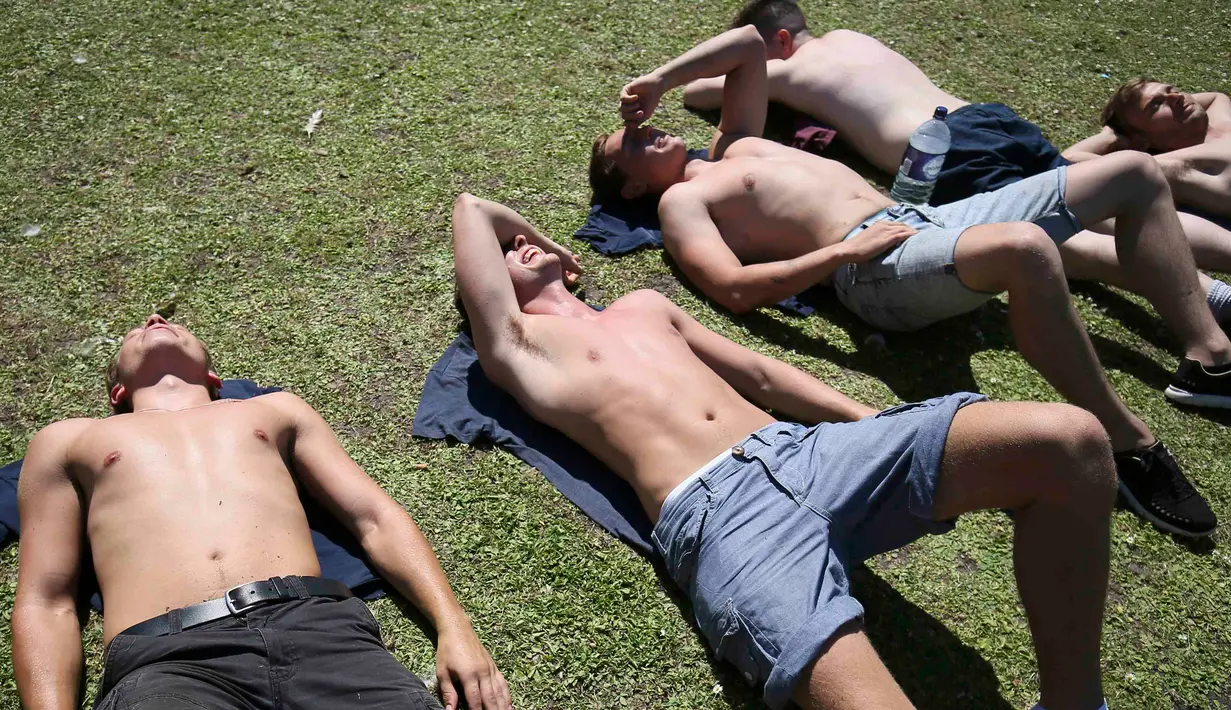 Sejumlah pria berjemur di Regents Park, London, Inggris, Selasa (19/7). Cuaca panas yang melanda Inggris dimanfaatkan warga untuk berjemur. (REUTERS/Neil Hall)
