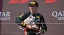 Pembalap Red Bull Racing, Max Verstappen berjalan meninggalkan podium sambil membawa trofinya yang pecah pada Formula 1 GP Hungaria di Sirkuit Hungaroring, Mogyorod, Hungaria, Minggu (23/07/2023). (AFP/Attila Kisbendek)