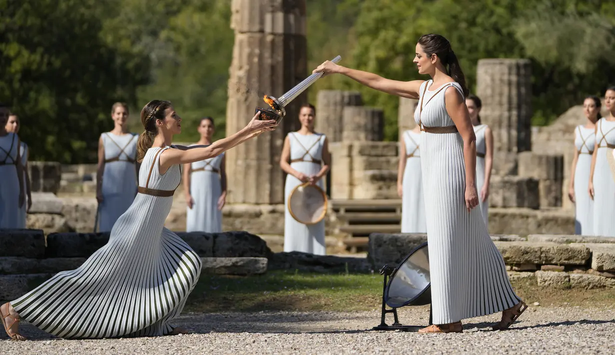 Aktris Yunani Xanthi Georgiou (kanan) berperan sebagai High Priestess memegang obor saat menyalakan api Olimpiade di situs Olympia, Yunani, Senin (18/10/2021). ​Nyala api akan dibawa dengan obor estafet ke Beijing yang menjadi tuan rumah Olimpiade 2022. (AP Photo/Thanassis Stavrakis)