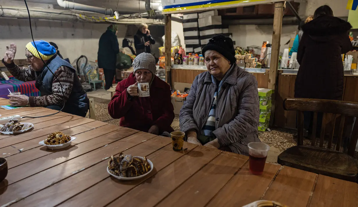 Penduduk setempat berkumpul di ruang bawah tanah di bawah pemadaman listrik di kota Bakhmut, Ukraina timur (22/12/2022). Mereka mencari perlindungan karena penembakan hebat oleh pasukan Rusia. (AFP/Sameer Al-Doumy)