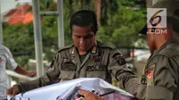 Petugas Satpol PP menertibkan alat peraga kampanye (APK) di jembatan penyeberangan orang (JPO) kawasan Gambir, Jakarta, Sabtu  (22/12). Penertiban itu dilakukan karena melanggar aturan pemasangan dari komisi pemilihan umum. (Liputan6.com/Faizal Fanani)