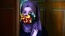 Seorang perempuan mengenakan topeng yang dihiasi kelopak bunga di tengah virus corona (Covid-19) di pusat kota suci Najaf, Irak pada 21 Maret 2020. Masker dijadikan masyarakat pilihan untuk mencegah penyebaran pandemi virus corona yang terus meningkat di seluruh dunia. (Haidar HAMDANI/AFP)