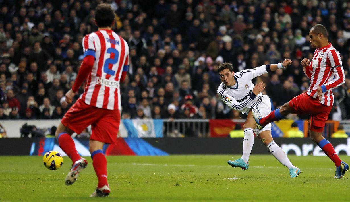 Gelandang Real Madrid, Mesut Oezil (tengah) mencetak gol ke gawang Atletico Madrid pada laga Liga Spanyol 2012/2013 di Santiago Bernabeu Stadium, Madrid (1/12/2012). Mesut Oezil tercatat membuat 4 gol dan 2 assist ke gawang Atletico Madrid dari total 10 pertemuan saat berseragam Arsenal dan Real Madrid. Seluruh gol dan assist dicetak bersama Real Madrid sejak musim 2010/2011 hingga 2012/2013. (AFP/Cesar Manso)