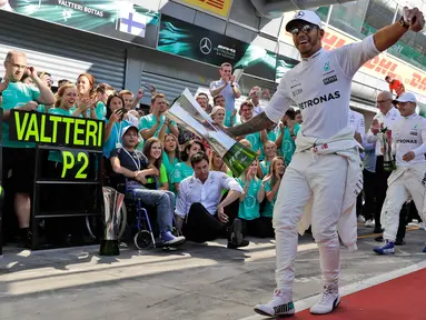 Lewis Hamilton merayakan kemenangannya dalam balapan F1 GP Italia, di arena Monza, Italia (3/9). Hamilton keluar sebagai juara pada balapan F1 GP Italia dengan keunggulan 4,4 detik atas Valtteri Bottas yang finis kedua. (AP Photo/Luca Bruno)