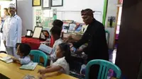 Abah Uju (berbaju hitam), pendiri Ontel Pustaka kini membuka perpustakaan mini di rumahnya. (Liputan6.com/Abramena)