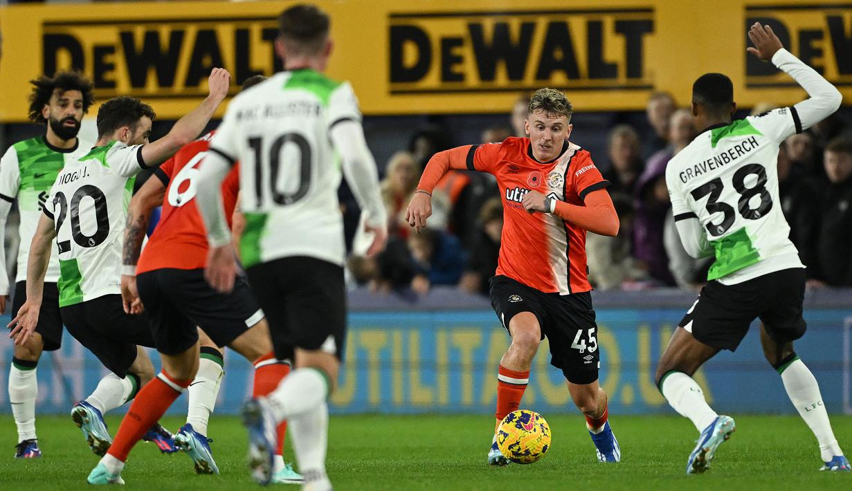 Gelandang Luton Town, Alfie Doughty (tengah) berusaha melewati gelandang Liverpool, Ryan Gravenberch (kanan) pada laga pekan ke-11 Liga Inggris 2023/2024 di Kenilworth Road Stadium, London, Minggu (5/11/2023) malam WIB. (AFP/Justin Tallis)