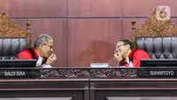 Ketua Mahkamah Konstitusi (MK) Suhartoyo (kanan) berbicara dengan Hakim Konstitusi Saldi Isra (kiri) di sela sidang perkara Nomor 145/PUU-XXI/2023 di Gedung MK, Jakarta, Selasa (16/1/2024). (Liputan6.com/Angga Yuniar)