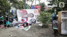 Warga korban kebakaran terlihat beristirahat dekat banner calon anggota legislatif (caleg) di Jalan Manggarai II, Tebet, Jakarta Selatan, Minggu (17/12/2023). (Liputan6.com/Faizal Fanani)