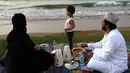 Sebuah keluarga Oman berkumpul untuk berbuka puasa di pantai di Muscat selama bulan suci Ramadhan pada 12 April 2022. Umat islam di seluruh dunia saat ini tengah melaksanakan bulan Ramadhan dan berpuasa selama satu bulan. (MOHAMMED MAHJOUB / AFP)