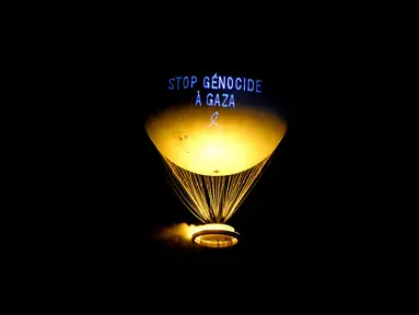 Sebuah pesan bertuliskan “Hentikan genosida di Gaza” diproyeksikan ke kaldron Olimpiade Paris 2024, yang dirancang oleh perancang Prancis Mathieu Lehanneur, di Paris, pada 26 Juli 2025. (Hugo MATHY/AFP)