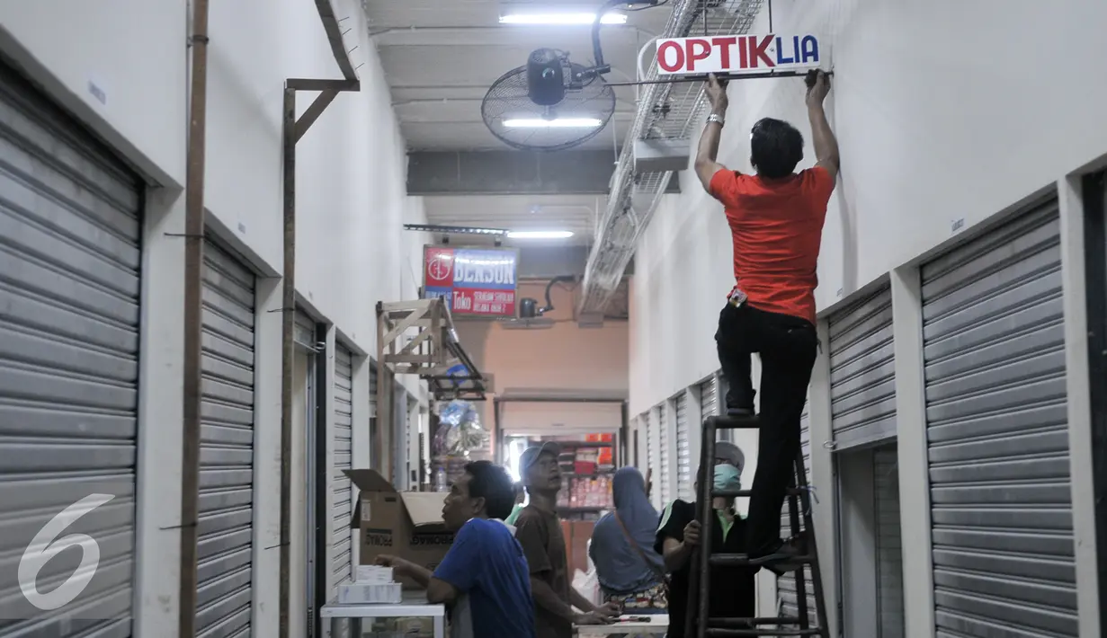 Pedagang memasang papan nama kiosnya di Tempat Penampungan Sementara (TPS), Manggarai, Jakarta, Selasa (4/10). Pedagang Pasar Rumput mulai tempati kios TPS Pasar Jaya Manggarai. (Liputan6.com/Yoppy Renato)