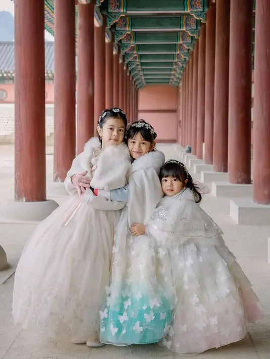 Ketiga putri Surya Insomnia tampil dengan hanbok musim dingin yang dilengkapi jaket putih berbulu. Rambutnya mengenakan bando bunga-bunga. [@suryainsomnia]