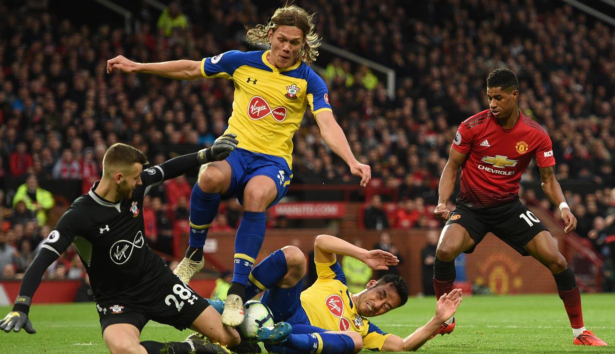 Kiper Southampton, Angus Gunn, berusaha mengamankan bola dari striker Manchester United, Marcus Rashford, pada laga Premier League di Stadion Old Trafford, Manchester, Sabtu (2/3). MU menang 3-2 atas Southampton. (AFP/Oli Scarff)