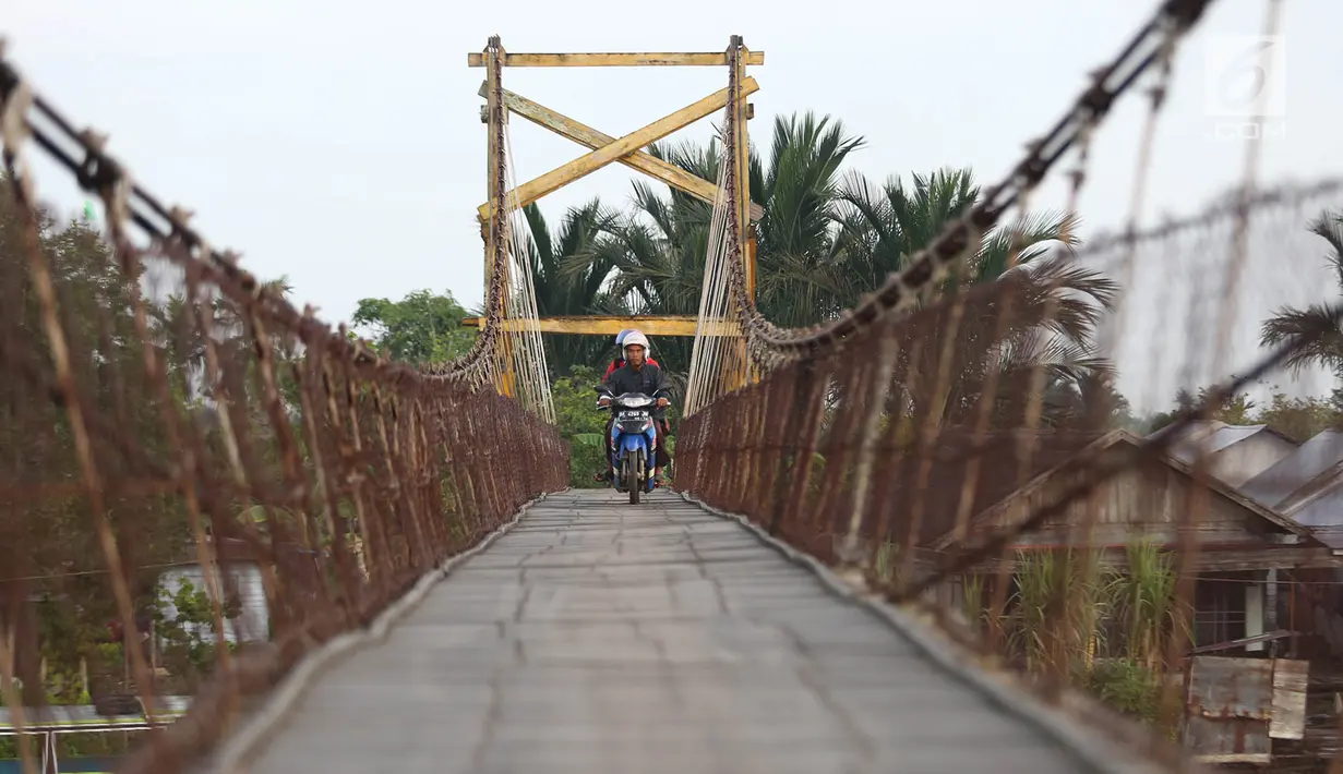 Warga melintasi jembatan penyeberangan di Sungai Martapura, Banjarmasin, Kalimantan Selatan, Selasa (27/3). Selain perahu, jembatan tersebut menjadi satu-satunya akses menyeberang bagi warga sekitar. (Liputan6.com/Immanuel Antonius)